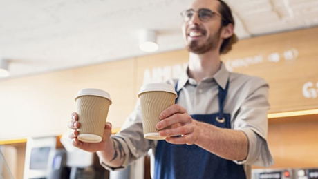 Barista serving beverages in disposable paper cups