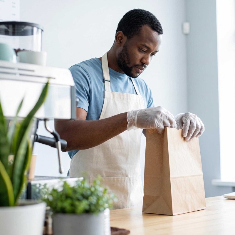Foodservice worker packing takeaway with gloves